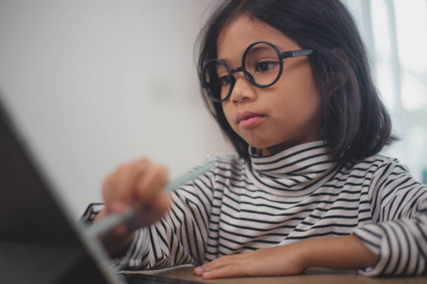istock Cute Asian little girl children using a laptop computer, studying through an online e-learning system. 2108716890