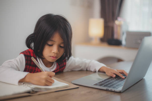 istock Cute and happy little Asian girl children using a laptop computer, studying through an online e-learning system at home. 2108733607