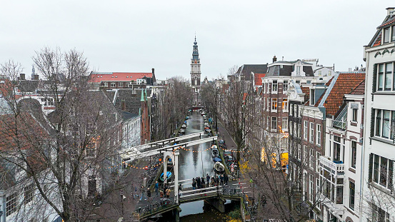 Protestant church Zuiderkerk Staalmeestersbrug bridge, aerial view of the canal leading to the Zuiderkerk church in Amsterdam,  canal in Amsterdam, Groenbuigwal canal towards the Zuiderkerk church, aerial view of the Staalmeestersbrug bridge\n\nThe Staalmeestersbrug is a classic Dutch draw bridge in Staalstraat, that crosses the romantic canal Groenburgwal. With the Zuiderkerk tower in the background, the bridge offers a splendid location to take pictures.\n\nThe Zuiderkerk is a 17th-century Protestant church in the Nieuwmarkt area of Amsterdam, the capital of the Netherlands. The church played an important part in the life of Rembrandt and was the subject of a painting by Claude Monet.\n\nThe church is open to the public and currently serves as a municipal information center with exhibitions on housing and the environment.