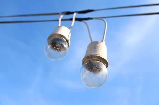 Equipped and electrical with light bulbs is hanging in the wind and sunlight on blue sky