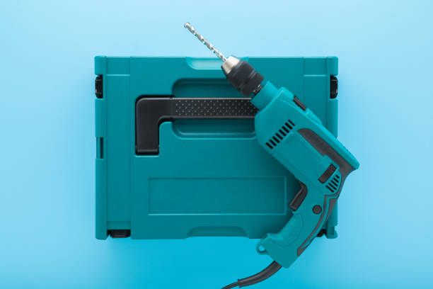 istock New dark black green professional electric hammer driver drill on plastic toolbox on light blue table background. Pastel color. Closeup. Tool for repair work. Top down view. 2108832556