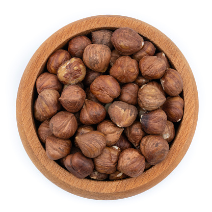 Raw Hazelnut in wooden bowl isolated on white background.