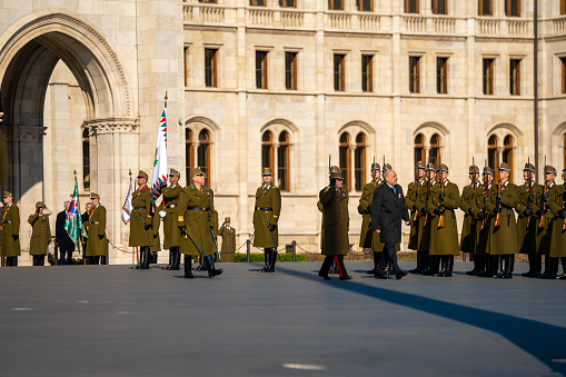 Budapest, Hungary - March 15, 2024: National day celebration near the parliament building. Military parade with military band. Acting President Tamas Sulyok on the middleground.
