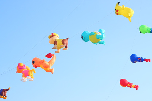 Can Tho, Vietnam - March 19, 2024: Colorful kites flying in the clear blue sky background - popular outdoor toys at Mekong Delta Vietnam. Happy childhood moments.