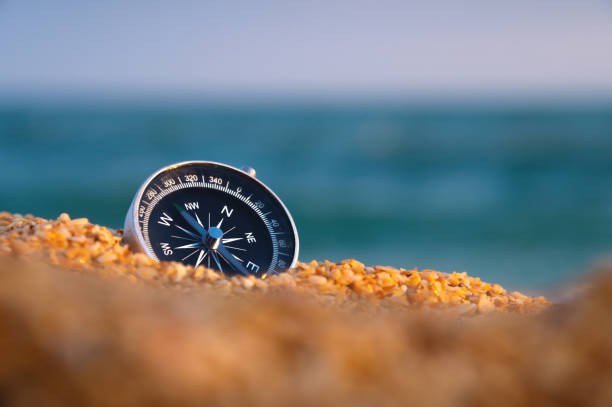konceptualne zdjęcie kompasu w gruboziarnistym piasku na tle morza i nieba, zbliżenie, bez ludzi - compass exploration the way forward beach zdjęcia i obrazy z banku zdjęć
