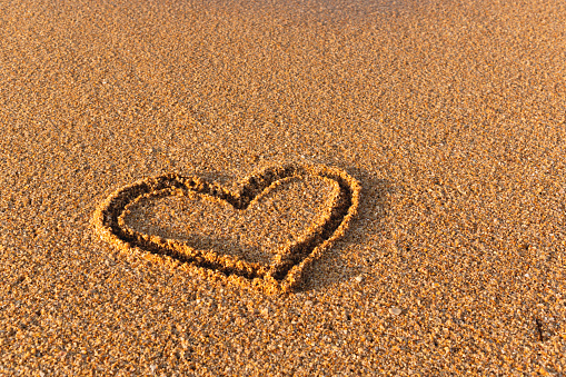 Heart drawn in the sand. Beach background. Top view.