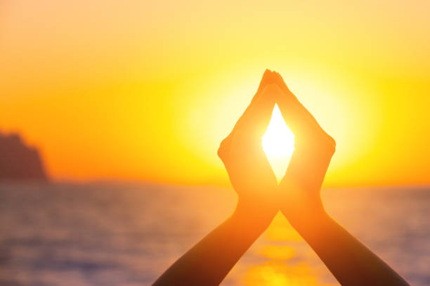 International Yoga Day concept raised hands catching the sun in the sunset sky with the sea in the background. International Yoga Day concept raised hands catching the sun in the sunset sky with the sea in the background religion sunbeam one person children only stock pictures, royalty-free photos & images