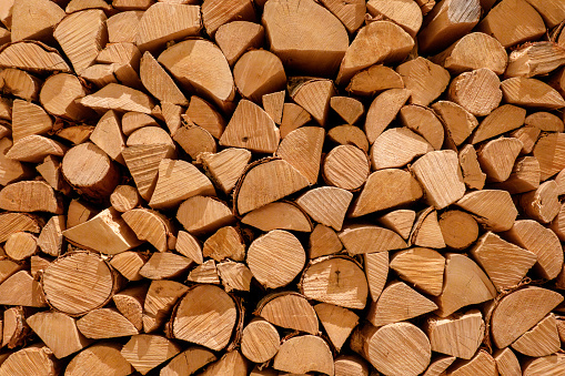 Stack of brown cut logs of pine firewood in neat pile