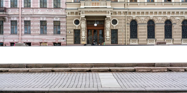 Long horizontal blank billboard above street level with classic architectural elements and cobblestone street in background. Offers ample space for advertising in a historic urban setting.