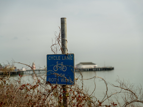 Cycle lane sign on the clifftop of Clacton-on-Sea beach with the pier in the background