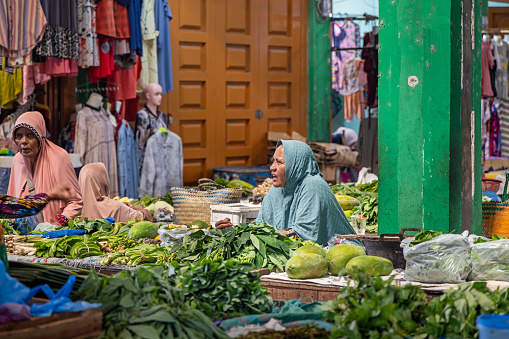 Sabang, Pulau Weh, Indonesia - January 14th 2024: Female greengrocer at a market stall in the marked hall in the city of Sabang which in the main city on the island Weh north of Sumatra