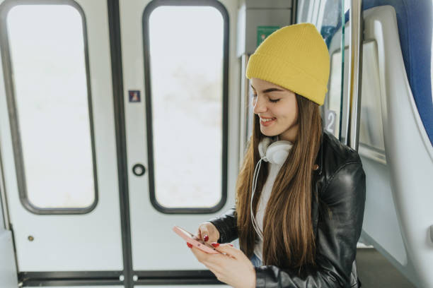 istock Beautiful young woman using smart phone while traveling by train 2109006651