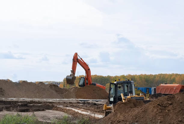 istock Excavator during earthmoving at open pit on blue sky background. Construction machinery and earth-moving heavy equipment for excavation, loading, lifting and hauling of cargo on job sites 2109007175