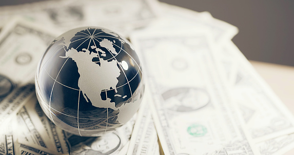 glass miniature globe against the background of American dollar bills