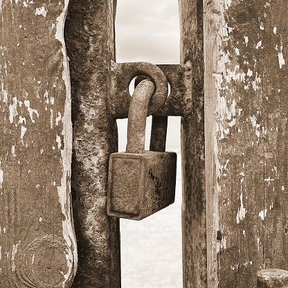 Sepia-Toned Vintage Padlock On Weathered Wooden Gate With Rustic Charm
