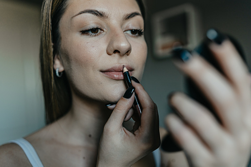 A woman adds the final touch to her look with the application of lipstick, a simple act that embodies elegance and confidence. This moment is a testament to the transformative power of makeup in enhancing personal style and expression