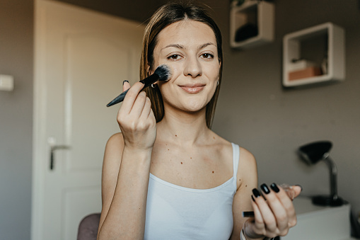 A woman enhances her beauty one layer at a time, starting with foundation. This process at home is a ritual of self-appreciation and an acknowledgment of her unique beauty