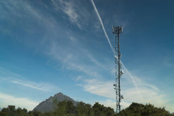 Tall communication towers standing against a vivid blue sky, illustrating infrastructure and modern connectivity technology. This depiction showcases the elegance and functionality of towering antennas in an outdoor environment.