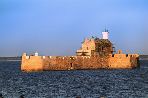 Pani Kotha prison in the distance. Shows the blue water, waves, ocean Walls of diu fort with view of Old Diu City, Portuguese, located in Diu district of Union Territory Daman and Diu India