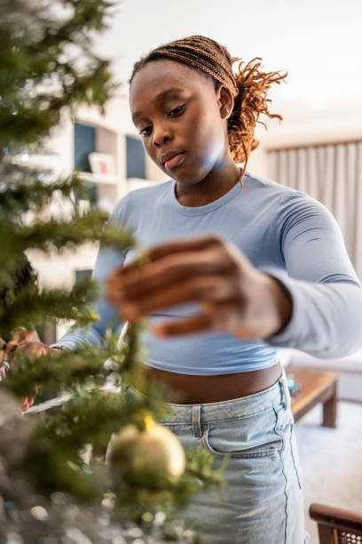istock Young african girl decorating a Christmas tree at home 2109187364