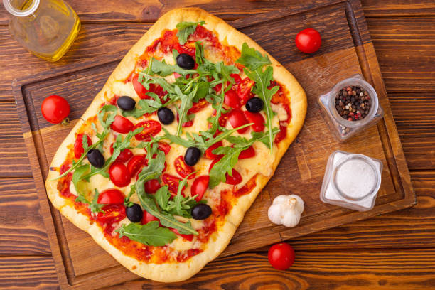Traditional italian pizza with vegetables tomatoes cherry , olives and  arugula . Pinsa Romana