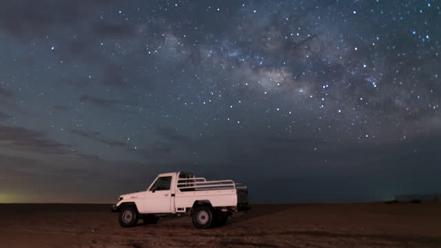 Time lapse of night sky milky way over camel farm camp in the desert of empty quarter