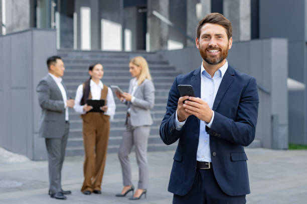 istock Business professionals using phones outside corporate building 2109225901