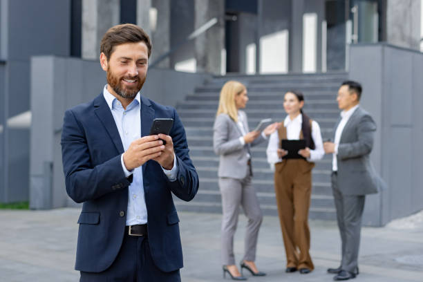 istock Businessman using smartphone with colleagues in background 2109232665