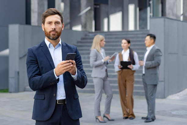 istock Businessman using smartphone with colleagues in background 2109235977