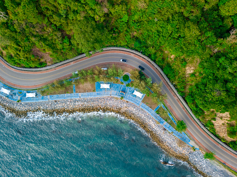 top view of a car driving on the curved road alongside the ocean beach road of Thailand. road landscape in summer. it's nice to drive on the beachside highway. Chantaburi Province Thailand,