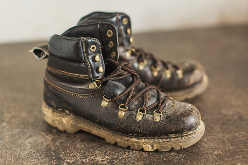 Old boots with mud and sand. Footwear