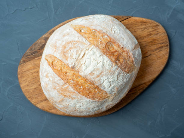istock Close-up of fresh crispy wheat bread of round shape on a wooden cutting board. Grey background. Top view ,flat lay 2109306607