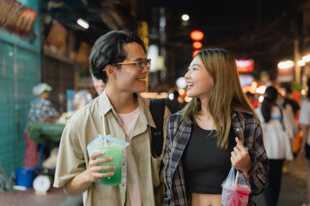 istock Couple with Drinks Walking in Night Market. 2109325790