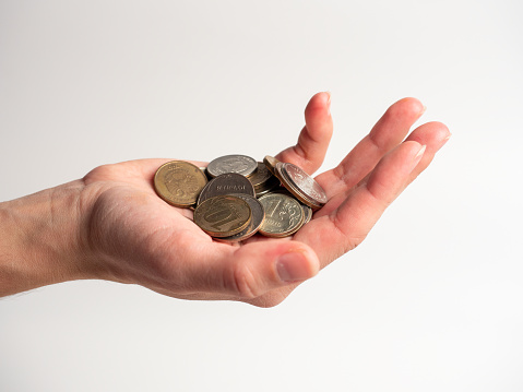 Close-up of a palm with a bunch of coins on a white background. Rubles, the concept of an economic crisis and the depreciation of money. Poverty, side view