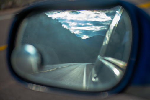 Through the rear-view window, the car captures a snapshot of the road, offering a glimpse of the journey's perspective and traffic behind.