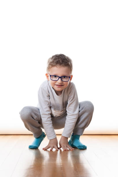 A young boy with glasses crawling on the floor