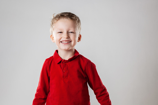 Portrait of a happy little boy standing upright smiling and looking at camera.