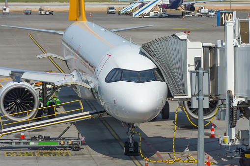 View of the nose and cockpit of the aircraft and the docking gangway air bridge. Maintenance and service of the flight before departure