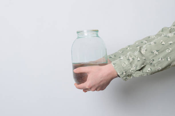 istock Women's hands hold a three-liter glass jar with clean water. 2109436604