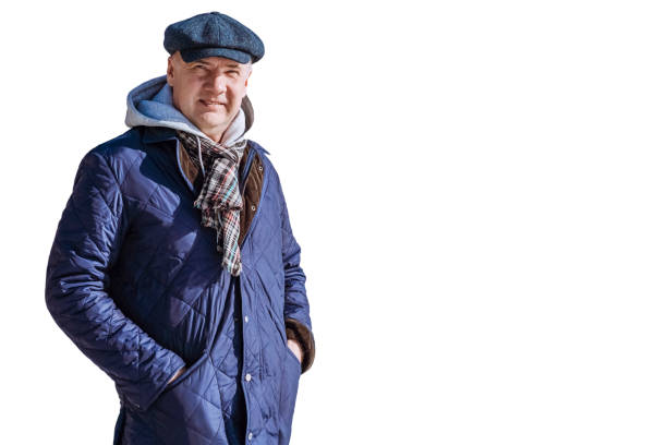 Portrait of smiling mature man standing on white background. Men is dressed in warm clothes, cap,  headdress, scarf,  jacket, down jacket