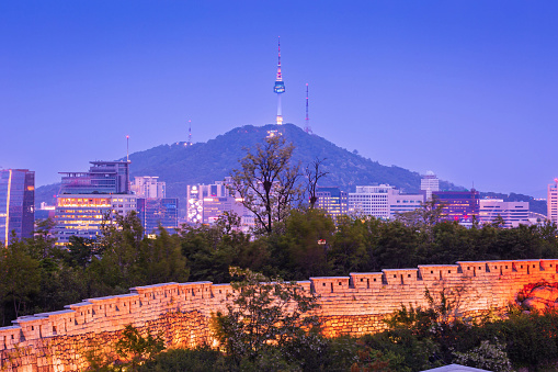 Seoul city at night and the ancient old wall, Namsan Mountain and Namsan Tower in the background, Seoul, South Korea.