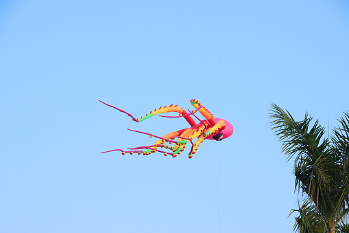 Colorful octopus kite flying in the clear blue sky in summer at Mekong Delta Vietnam. Happy childhood moments.