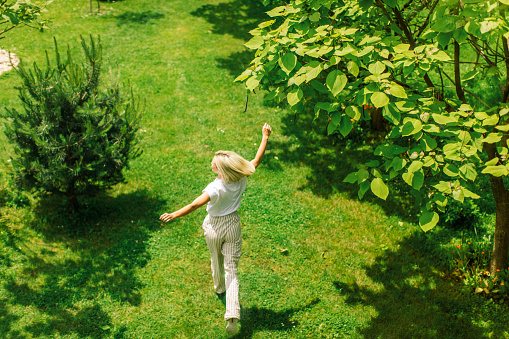 Young woman enjoying her time in the backyard. It's sprigtime and everything around her is green.