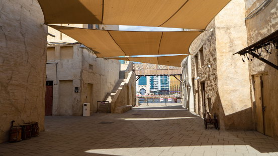 Street of Dubai old city Al Seef Khor in Al Fahidi neighborhood, United Arab Emirates. Waterfront promenade along bank of Dubai Creek.