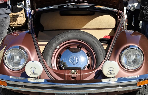 Udine, Italy. March 24, 2024 Spare tyre  inside an open front hood of vintage Volkswagen Beetle, or Type 1, during an antique car parade