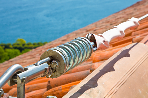 Horizontal lifeline fall protection system with inox stainless cable on terracotta roof used to prevent the danger of falling