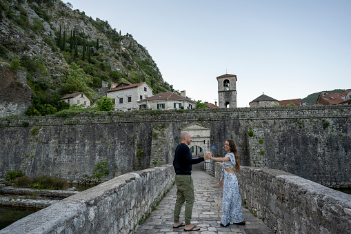Couple walk across stone bridge as they explore old town together