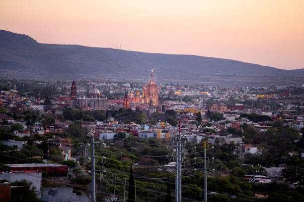 A view from a distant rooftop outside town of San Migue de Allende it's iconic Parroquia cathedral, lit up at dusk - known for its pink facade and Guaidiesque architecture. San Miguel is a world famous tourist destination