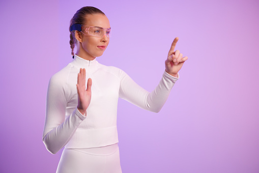 Young woman wearing smartglasses gesturing against purple background