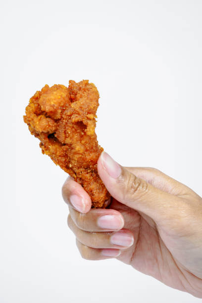 Female hand holding fried chicken on white background.